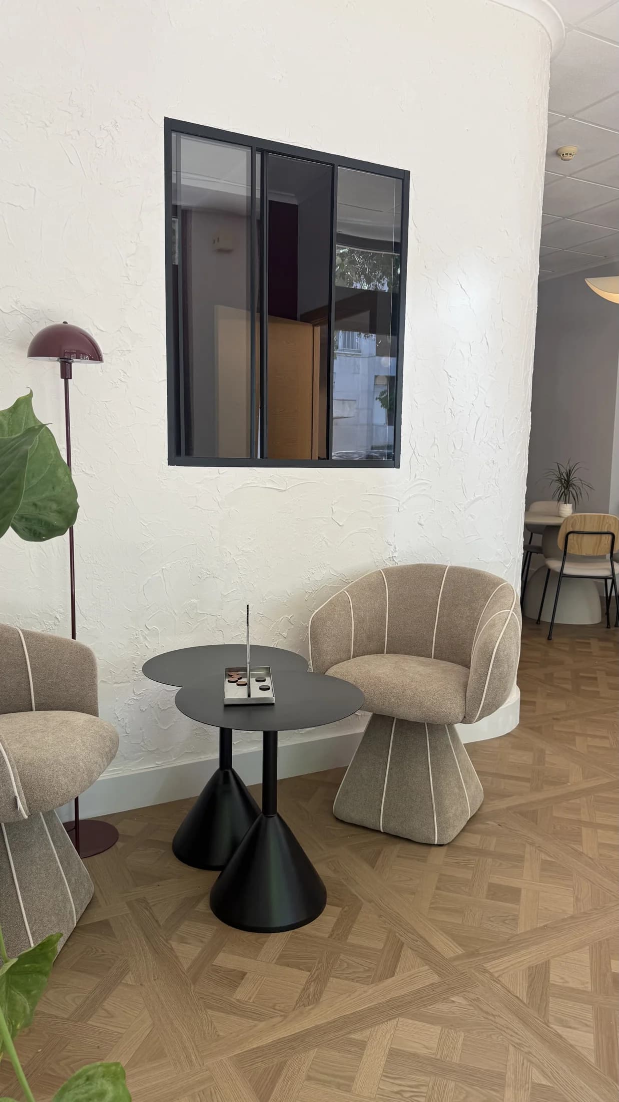 Duas poltronas estofadas com uma mesa pequena junto a uma janela interior