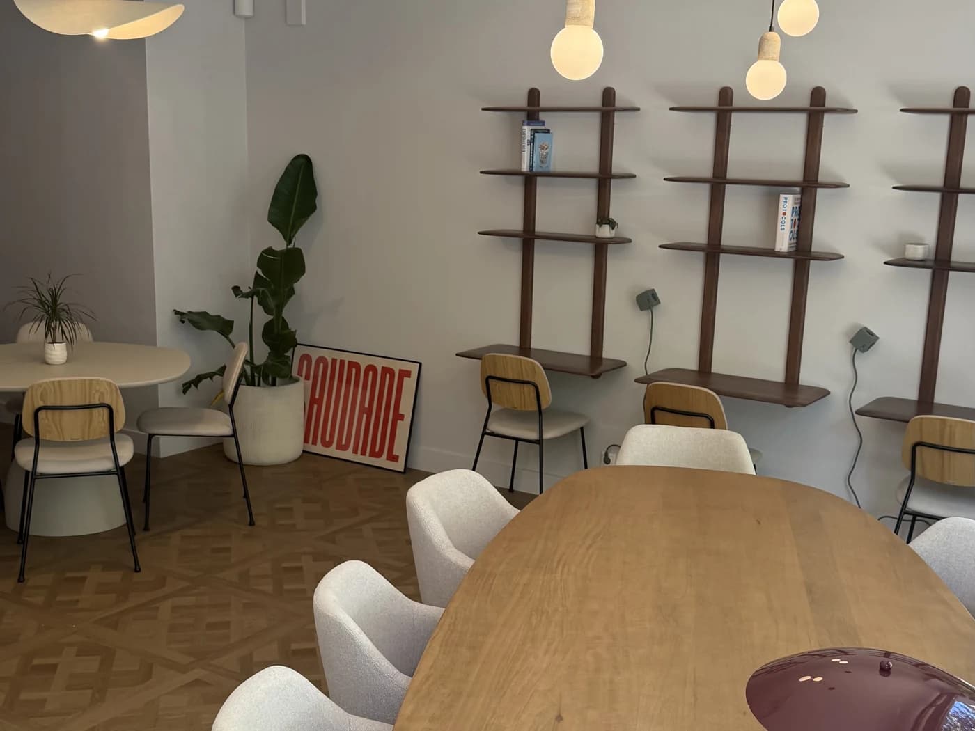 Interior do Elevada Club Cowork: mesa partilhada, cadeiras estofadas e prateleiras na parede